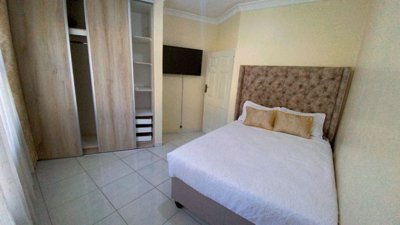 Een slaapkamer met een bed, een kledingkast en een televisie.