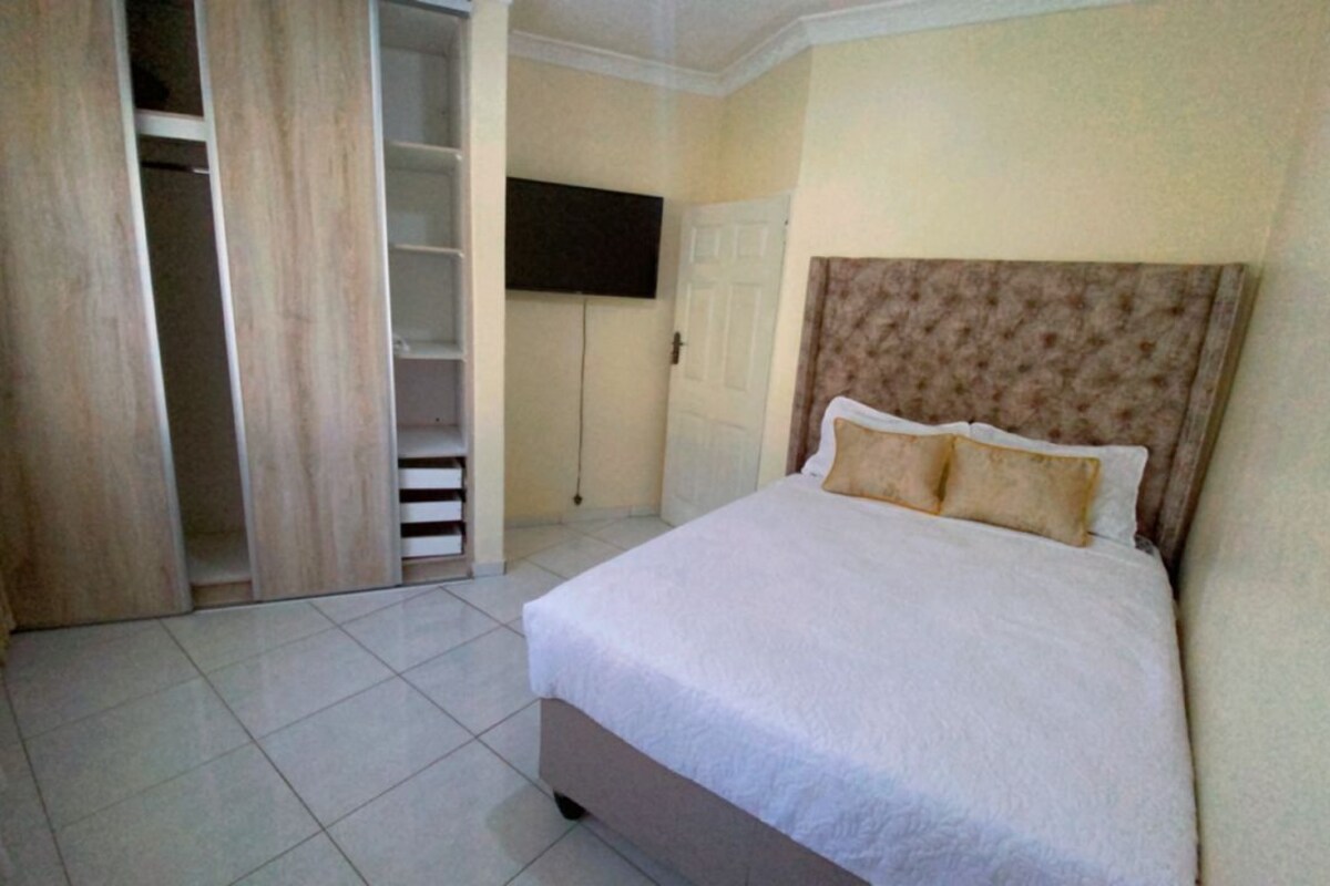 Een slaapkamer met een bed, een kledingkast en een televisie.