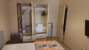 A bedroom with a bed, a wardrobe with hanging space, a radiator, and a quilt on the bed. - Diana's Suites Ephesus (Selçuk)