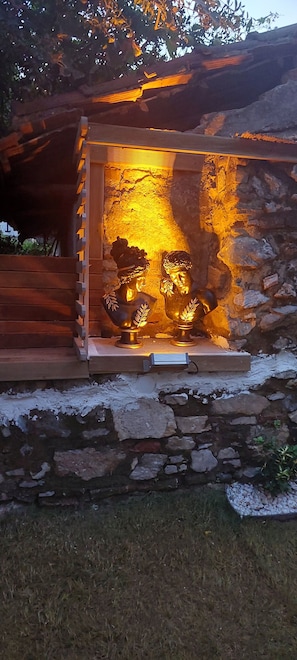 A stone wall with a wooden bench and a statue of a Buddha. - Diana's Suites Ephesus (Selçuk)