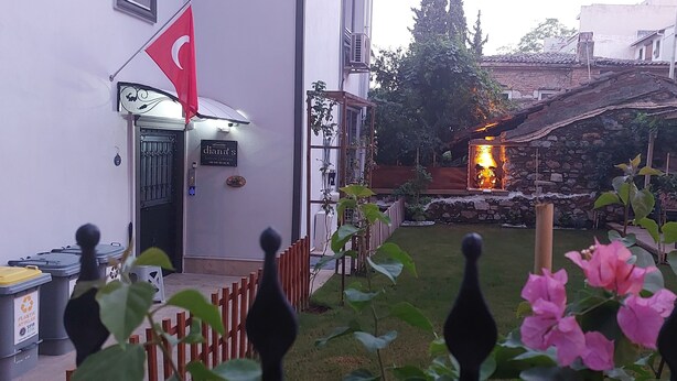 A courtyard with a stone wall, a fire pit, and potted plants. - Diana's Suites Ephesus (Selçuk)