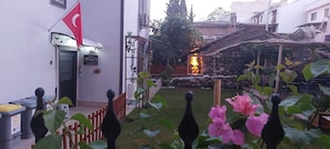 Un patio con un muro de piedra, una fogata y plantas en macetas.