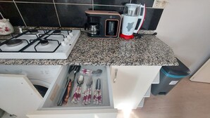 A kitchen with a gas stove, a coffee maker, and a drawer containing utensils. - Diana's Suites Ephesus (Selçuk)