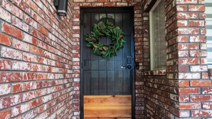 A brick building with a wooden door and a doormat. - Modern home 3-BR Retreat — Quiet, Cozy, & Family-Friendly in Fresno. (Fresno)