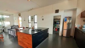 Eine moderne Küche mit einer zentralen Kochinsel, einem Essbereich mit einer Couch und einer Küchenarbeitsplatte mit einem Kühlschrank.