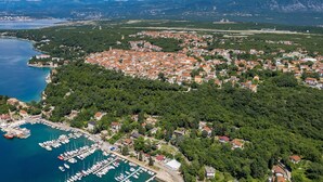 An aerial view of a coastal town with a marina, dense residential area, and surrounding mountains. - Nice apartment in Omisalj (Omisalj)