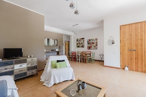 Un salon moderne comprenant un téléviseur, une table basse en verre, un canapé et un coin repas avec des chaises et une table.