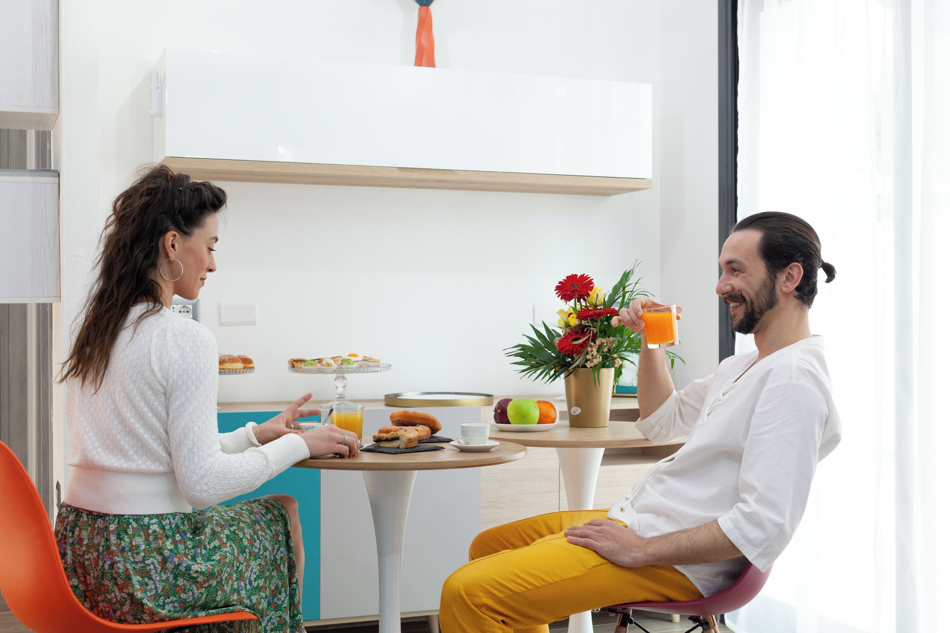 A breakfast setting with a table, chairs, and a vase of flowers.