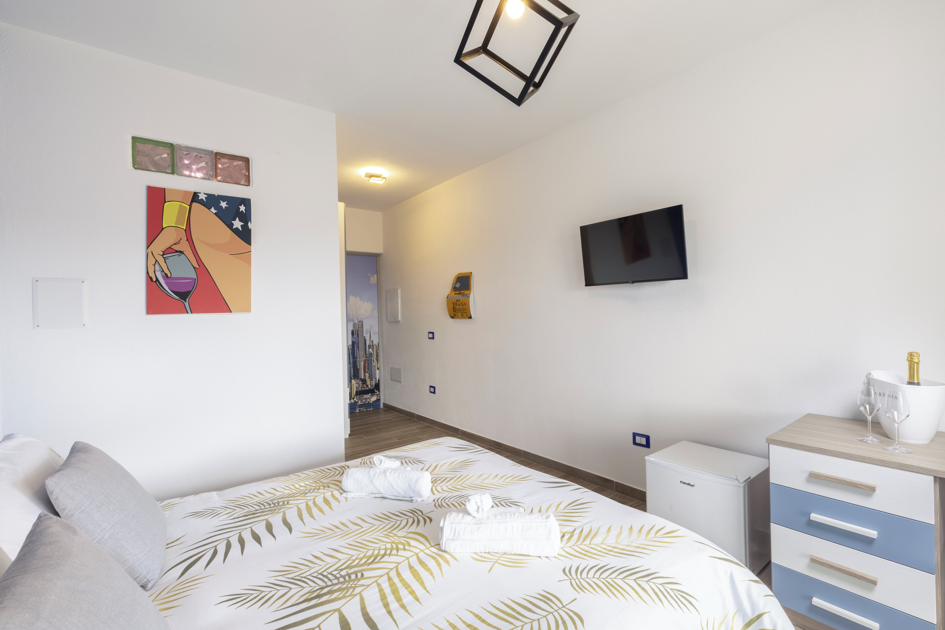Une chambre d’hôtel équipée d’un lit, d’une télévision, d’un mini-bar et offrant une vue sur le paysage urbain.