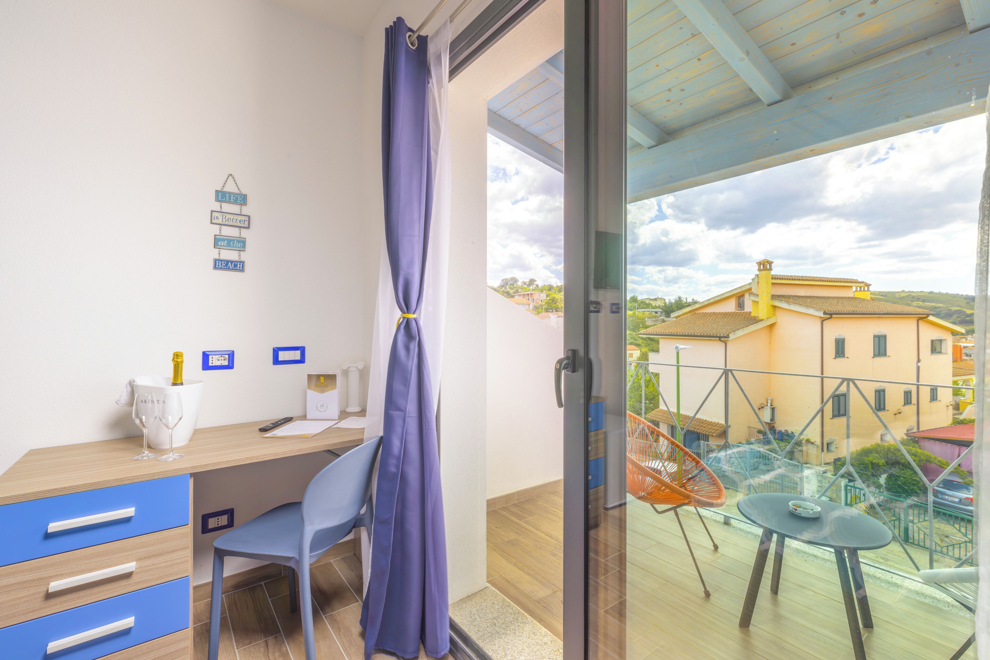 Une chambre équipée d’un bureau, d’une chaise et offrant une vue sur un balcon avec une table et des chaises.