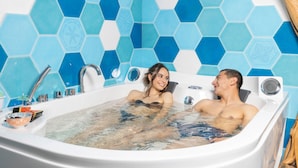 A couple in a bathtub with a blue hexagonal tile wall. - Agua Dorada Retreat (Lula)