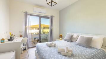 A hotel room with a bed, a desk, a chair, a lamp, and a view of the outside.
