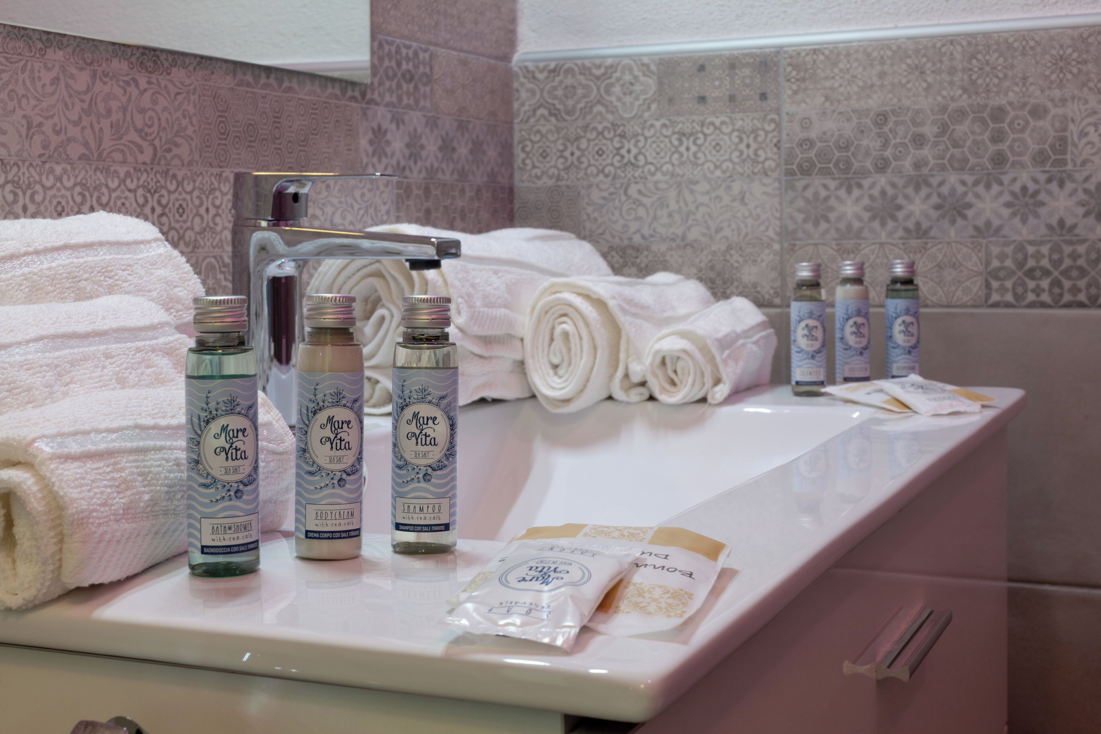 A bathroom counter with neatly folded towels, bottles of shampoo and conditioner, and a soap dispenser.