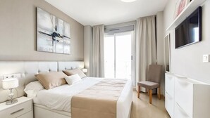 A modern bedroom with a large bed, a chair, a TV, and a window with curtains. - 1 bedroom beautiful apartment in Cabanes (Cabanes)