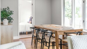 Un comedor con una mesa de madera, sillas negras y posavasos tejidos.