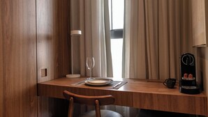 Una mesa de madera para comer con un plato, dos vasos, una taza y una cafetera.