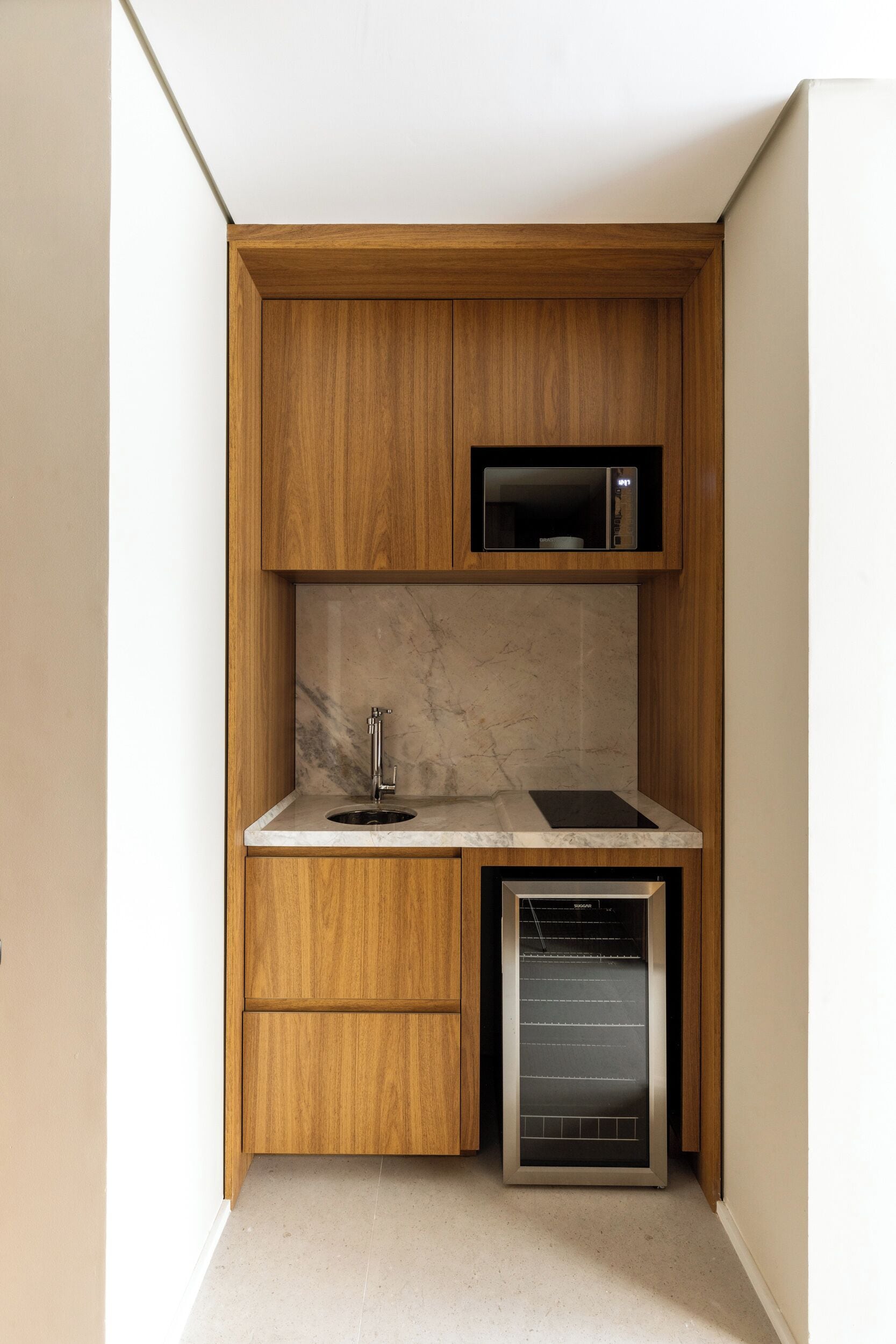 A compact kitchen with wooden cabinetry, a microwave, a sink, and a dishwasher.