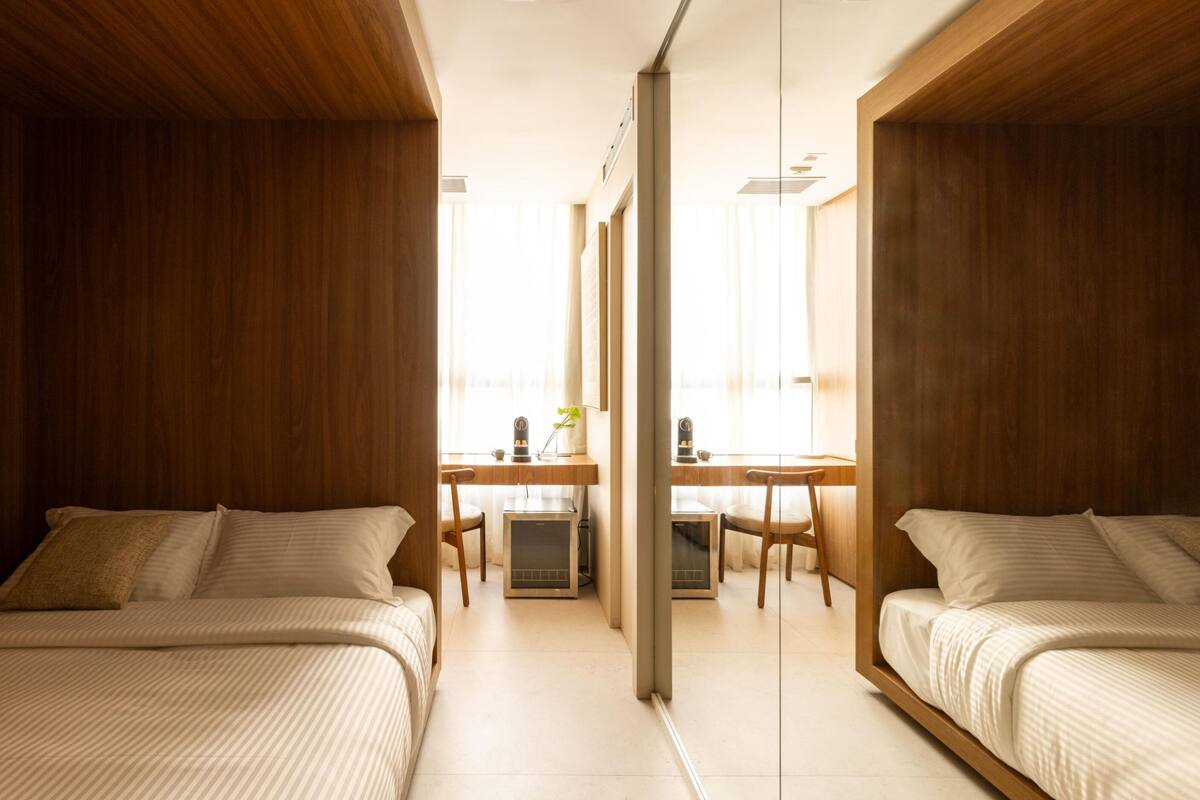 Une chambre d’hôtel moderne avec deux lits, un bureau et une chaise.