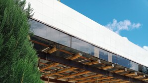 Un bâtiment moderne doté d’une façade en bois, de grandes fenêtres et d’un espace extérieur couvert.