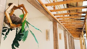 Un couloir doté d’une structure de plafond en bambou, d’un panier tressé suspendu au plafond et d’une plante en pot.