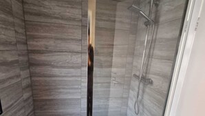 A shower with a glass door, a white bathtub, and a wooden floor. - Easy Rooms - London Luton Airport (Luton)