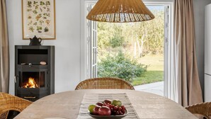A dining area with a table set for two, a fireplace, and a view of a garden through a glass door.