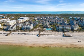 Vue aérienne d’un quartier résidentiel situé sur la côte, avec de nombreux immeubles, une plage et une vue dégagée sur l’océan.