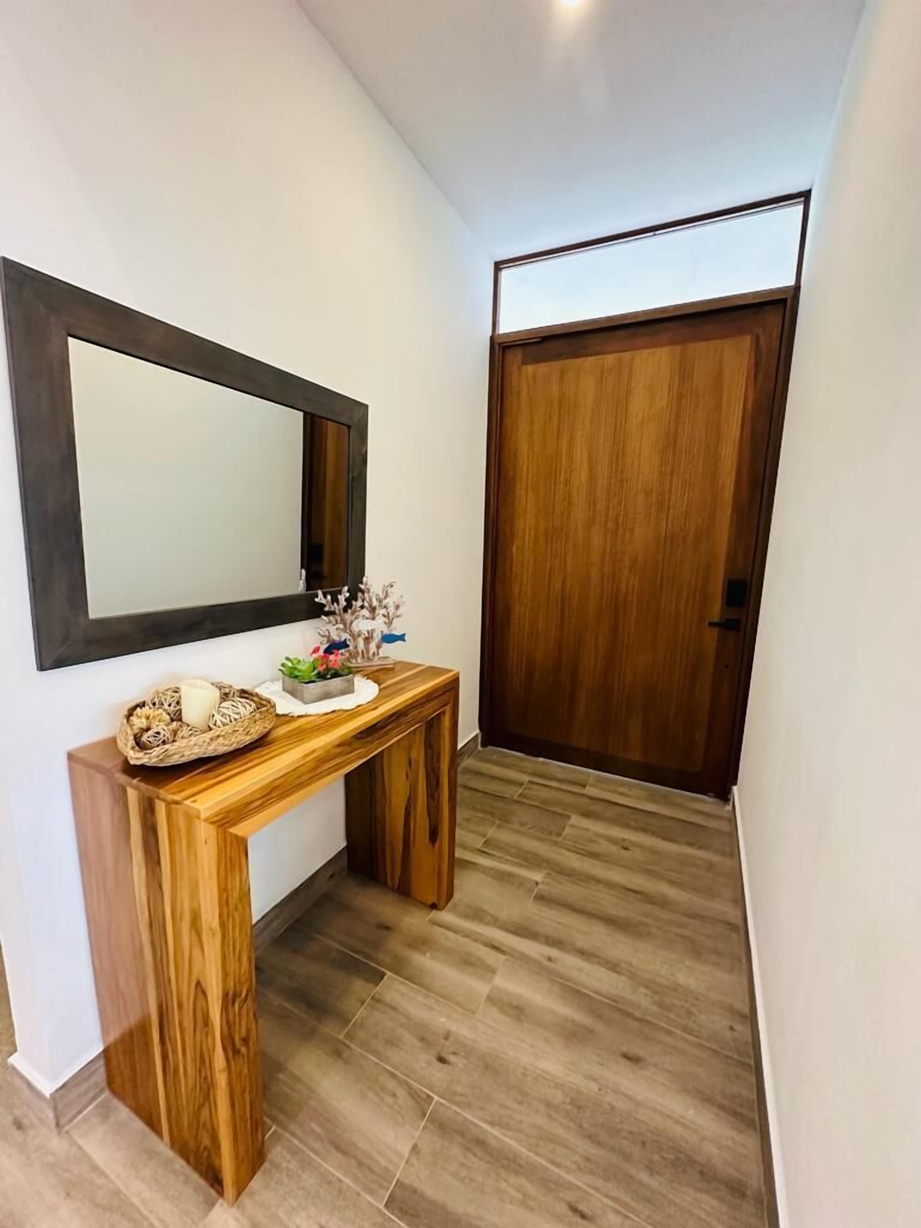 A hallway with a wooden console table, a mirror, and a wooden door.