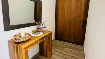 A hallway with a wooden console table, a mirror, and a wooden door.