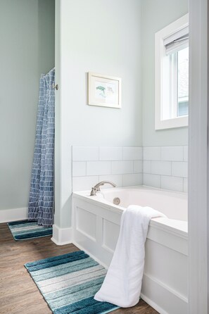 A bathroom with a white bathtub, a window, and a shower curtain. - Steps to Beach, Hot Tub, Gulf & Beach Views, Tiki Bar, Grill, Dogs, Games (Bolivar Peninsula)