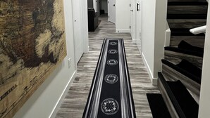 A hallway with a wooden map mural, a black and white patterned runner, and a staircase with wooden steps.