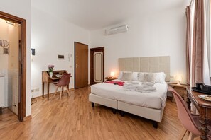 A hotel room with a bed, a desk, a chair, and a bathroom visible through an open door. - Leonardo - Sweet Dreams in Florence (Firenze)