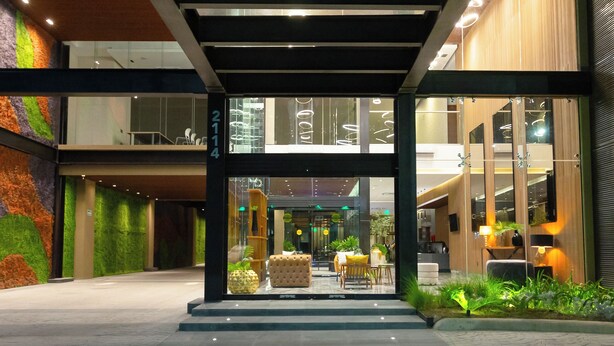 Un edificio moderno con entrada cubierta, paredes de vidrio y piso de baldosas.