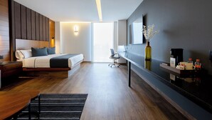 Una habitación de hotel moderna con cama, mesita de noche, escritorio, silla y un espejo grande.