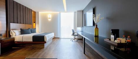 Ein modernes Hotelzimmer mit Bett, Nachttisch, Schreibtisch, Stuhl und einem großen Spiegel.