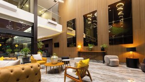 Un vestíbulo moderno con asientos cómodos, piso de mármol y un espejo grande que refleja el interior.