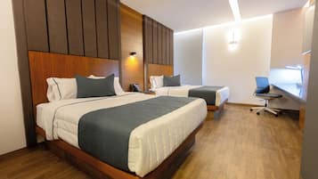 Habitación de hotel con dos camas, cabeceros de madera, un escritorio y una silla.
