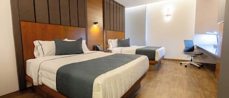 Habitación de hotel con dos camas, cabeceros de madera, un escritorio y una silla.