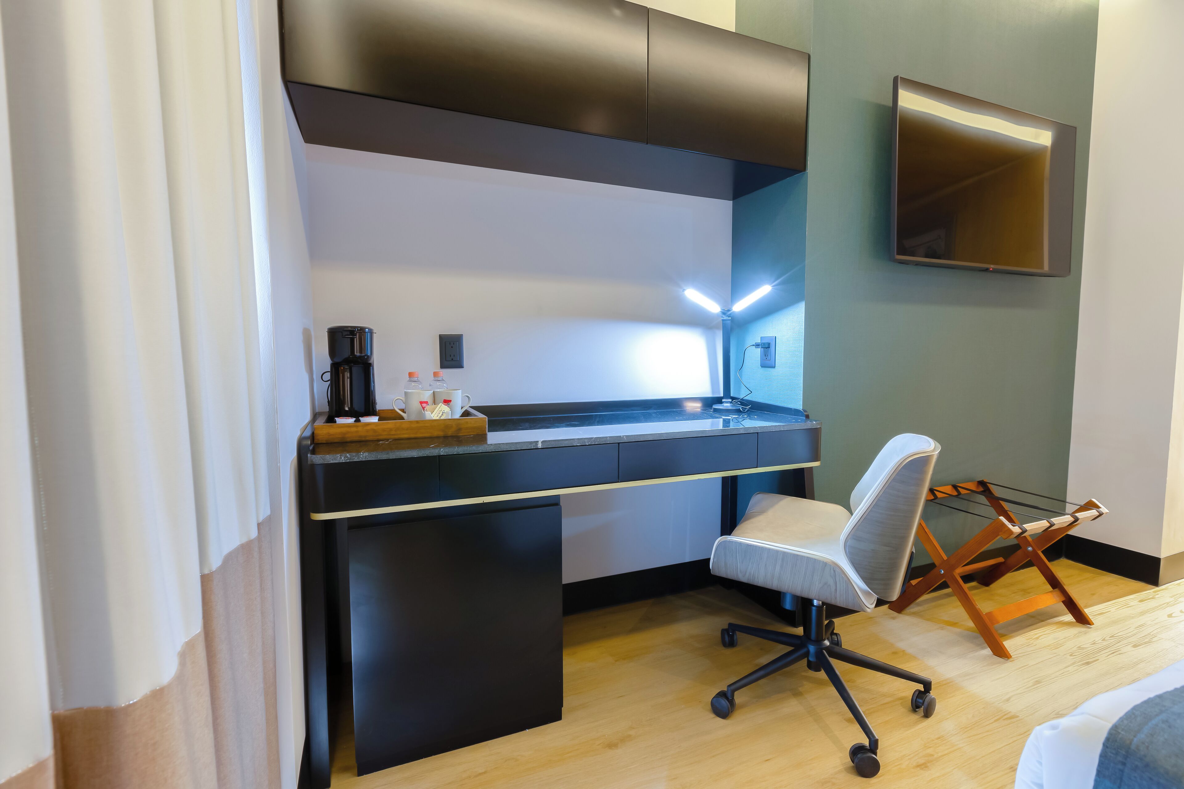 A modern hotel room with a desk, chair, and a large mirror.