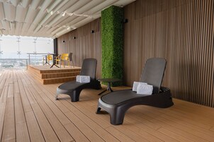 Een overdekt terras met twee lounge fauteuils, een tafeltje en een podium.