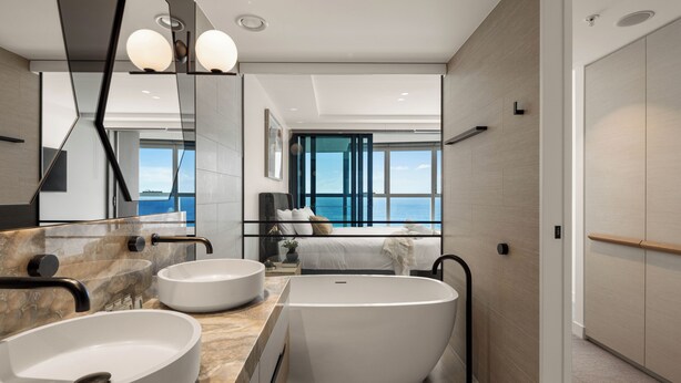A modern bathroom with a freestanding bathtub, two round sinks, and a large mirror. - Jewel Apartments by Coastal Letting Co (Surfers Paradise)