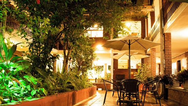 Un espace extérieur aménagé en terrasse, avec un sol en briques, des plantes en pot et des meubles de jardin agrémentés de parasols.