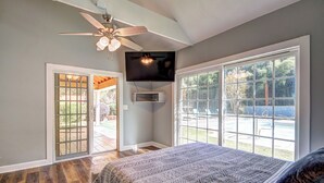 A bedroom with a large bed, a ceiling fan, a TV mounted on the wall, and a sliding glass door leading to a patio. - Pool vibes!  (Douglasville)
