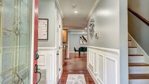 A hallway with wooden flooring, a white door with a glass panel, and a staircase with wooden steps. - Pool vibes!  (Douglasville)