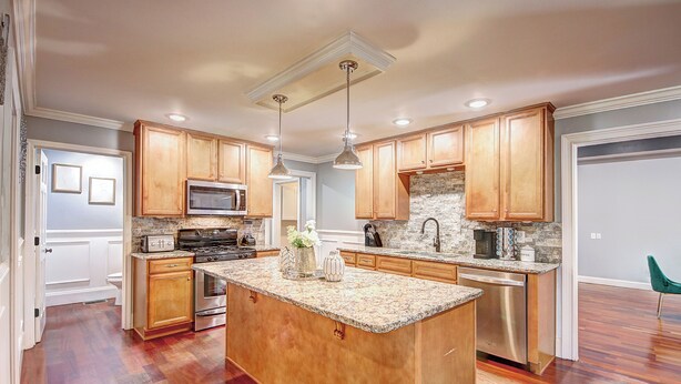 A spacious kitchen with wooden cabinets, granite countertops, stainless steel appliances, and pendant lighting. - Pool vibes!  (Douglasville)