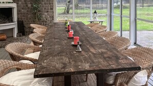 A long wooden table with wicker chairs, candles, and a view of a grassy area through large windows. - 4 bedroom beautiful home in Fleninge (Fleninge)