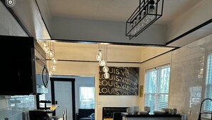 Una cocina moderna con una isla central, suelo de madera y una zona de comedor con sofá y mesa negros.