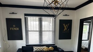 Una sala moderna con un sofá negro, una mesa de centro de vidrio y una lámpara de techo geométrica.