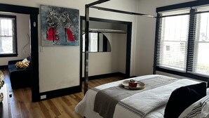 Un dormitorio con cama, un cuadro, un armario y una ventana.