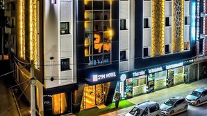A modern hotel with a prominent entrance, a visible restaurant, and a parking area with several cars. - Sym Hotel - Chéraga (Algiers)